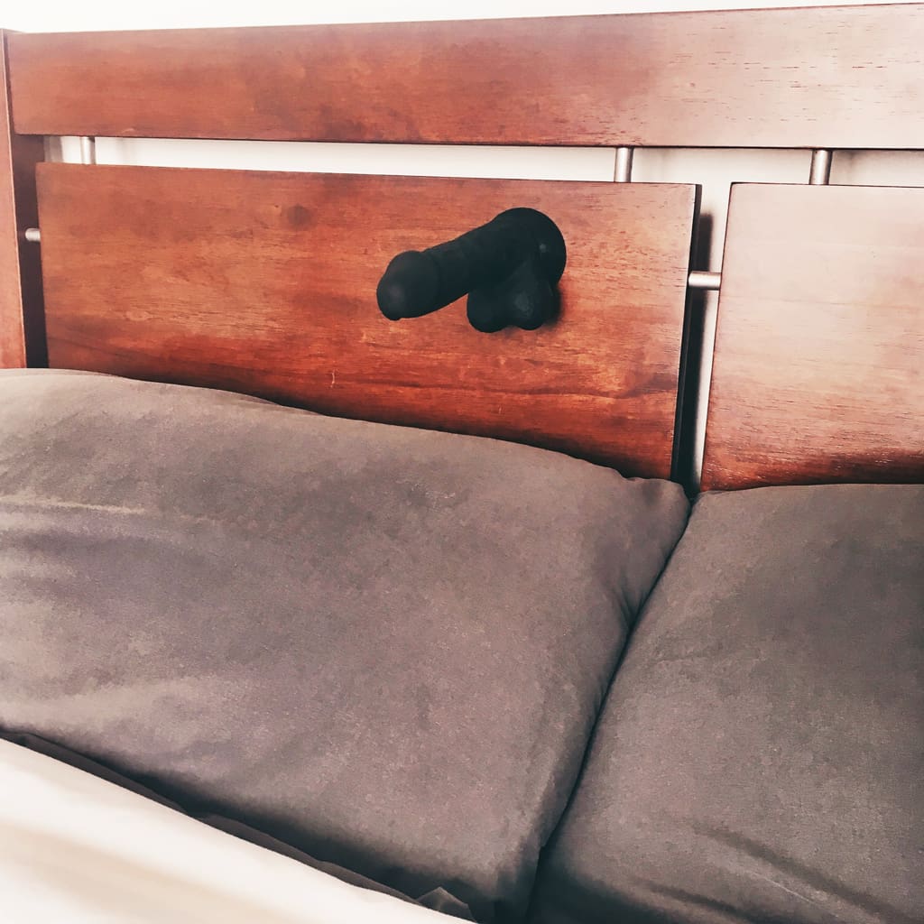 view of cloud9 dildo suctioned to bedroom headboard