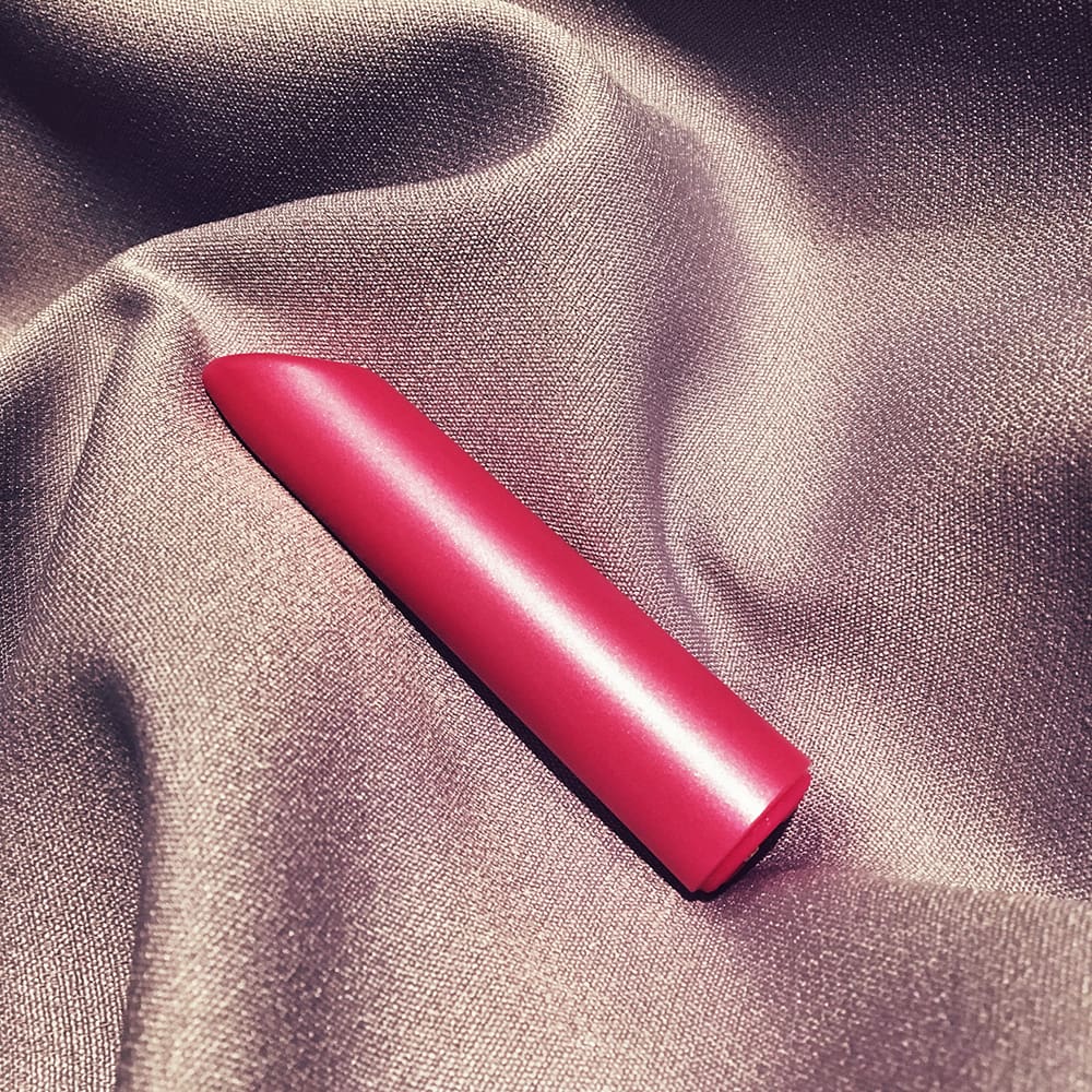 Photo of pink tube-shaped bullet vibrator on purple cloth