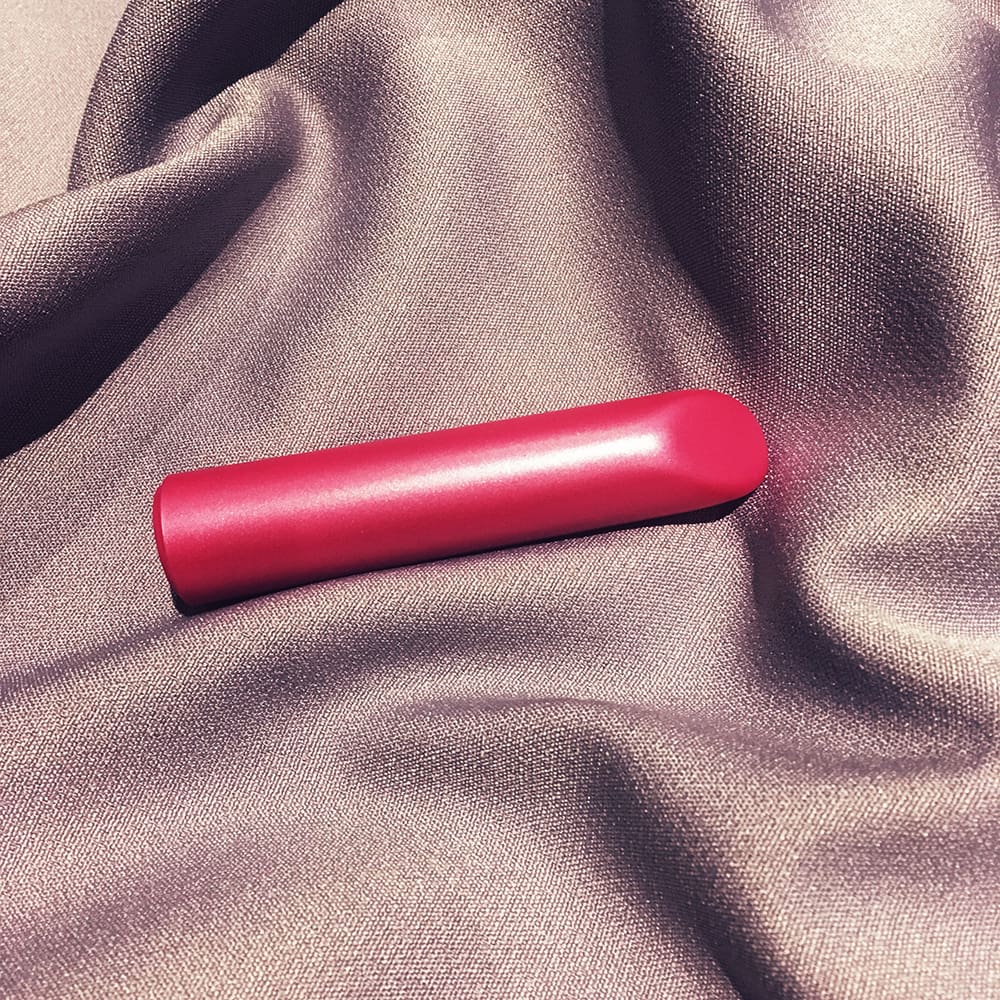 Photo of blush nocturnal lipstick vibe, tube shaped vibrator on cloth