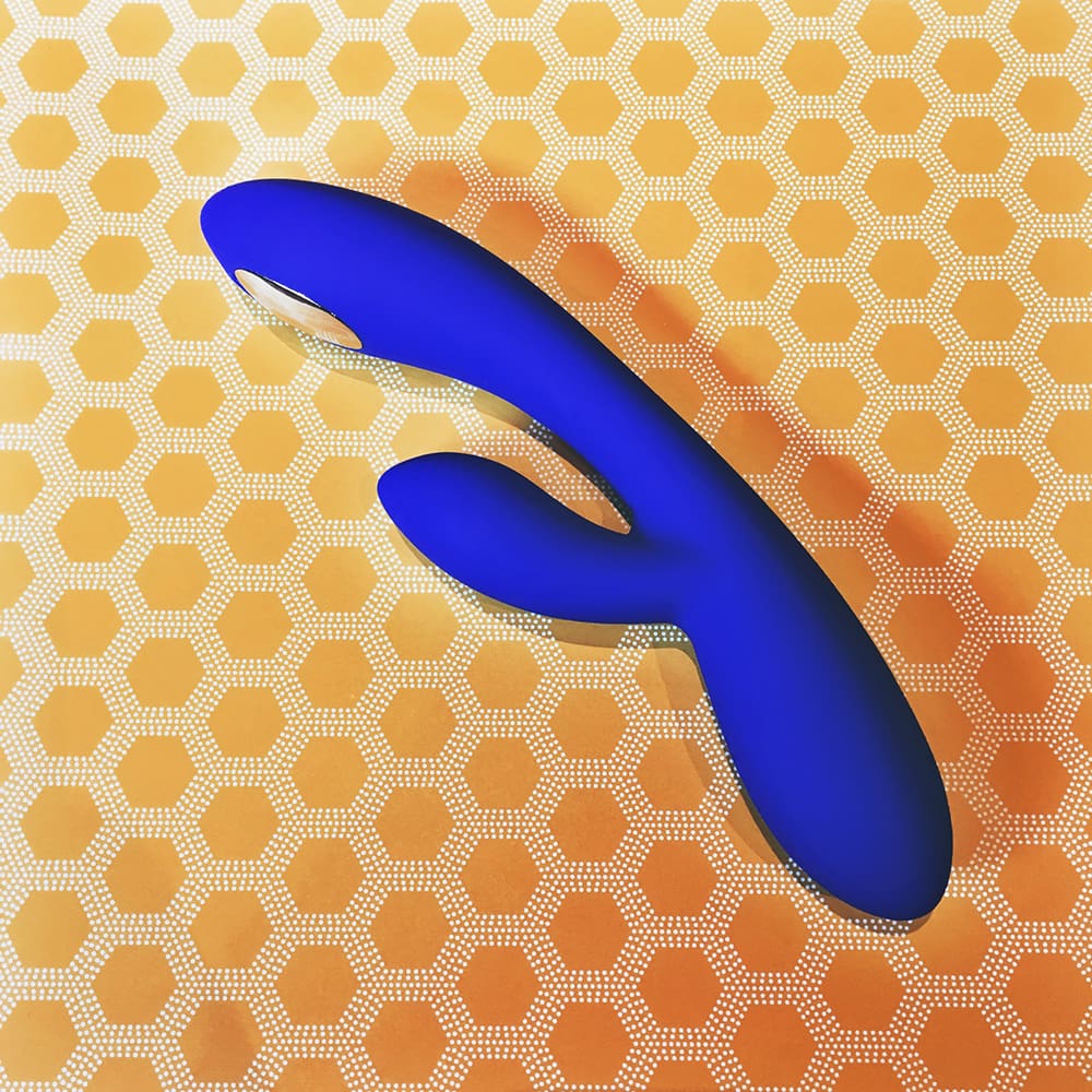Photo of blue rabbit-style vibrator on yellow heagonal pattern background