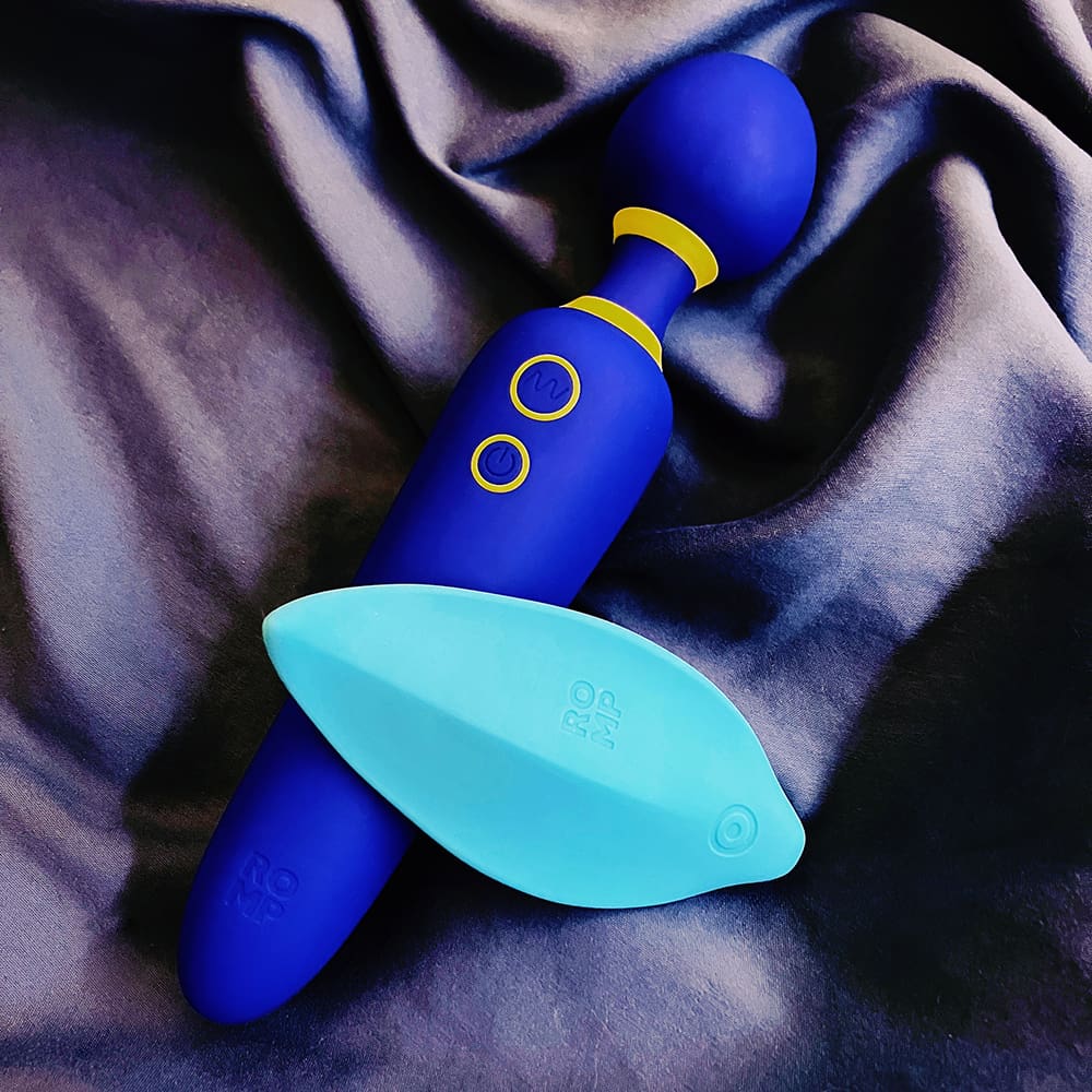 Photograph of teal ROMP Wave leaf-shaped clitoral vibe lying on top of blue ROMP Flip wand vibrator
