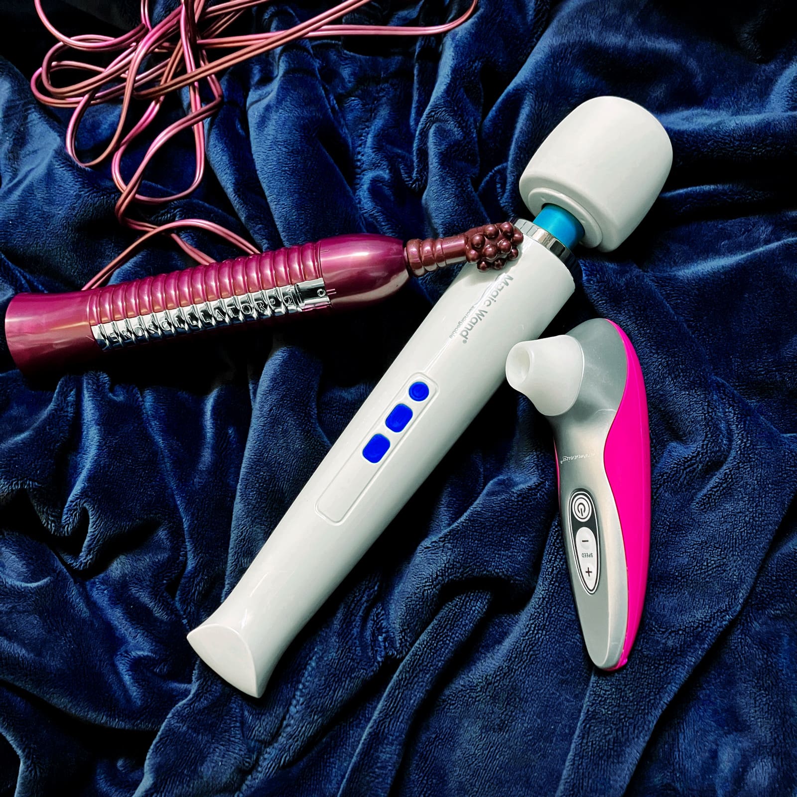 photograph of Hitachi magic wand, eroscillator, and womanizer pro40 on blue background