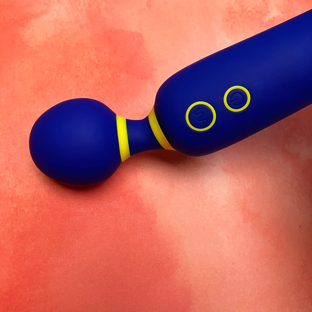 Photo of wand vibrator head pressed against the backdrop, causing the neck of the vibrator to bend slightly